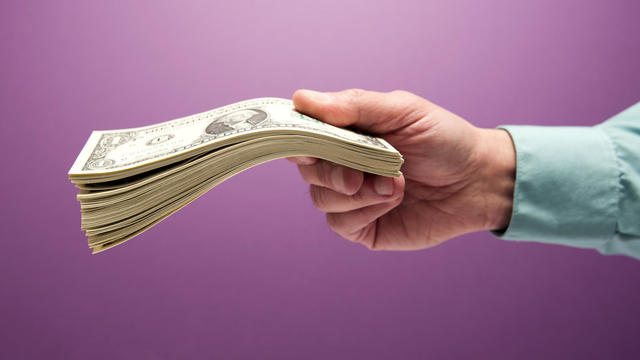 Man's hand holding stack of cash 